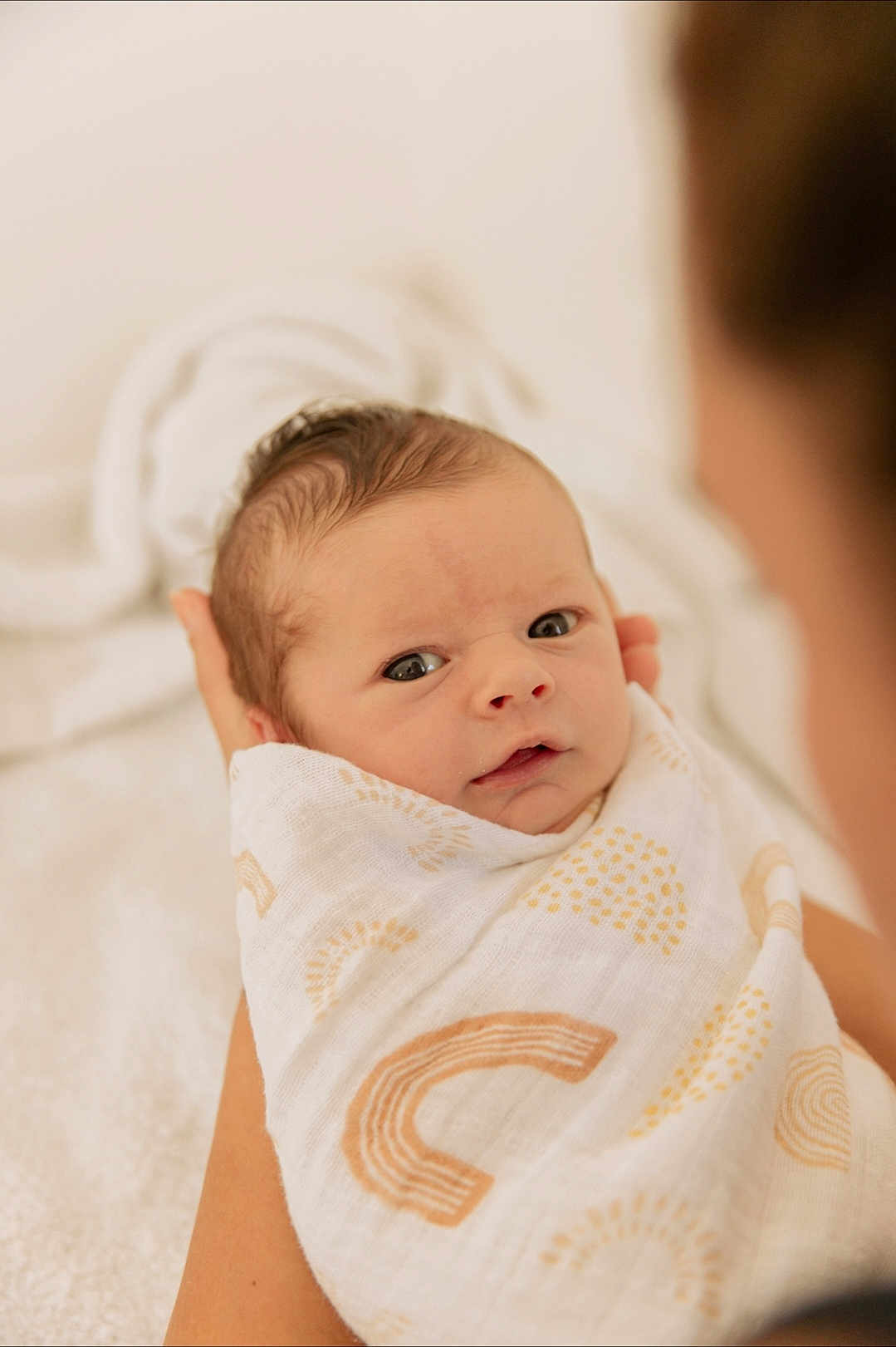 Lucas a rejoint le concours — aidez-le/la à gagner de superbes lots ! baby, swaddled, blanket, newborn, infant, person, face, eyes, hands, soft_focus, patterned_blanket, cradle, closeup, warmth, skin, head, expression, indoor, parent, care