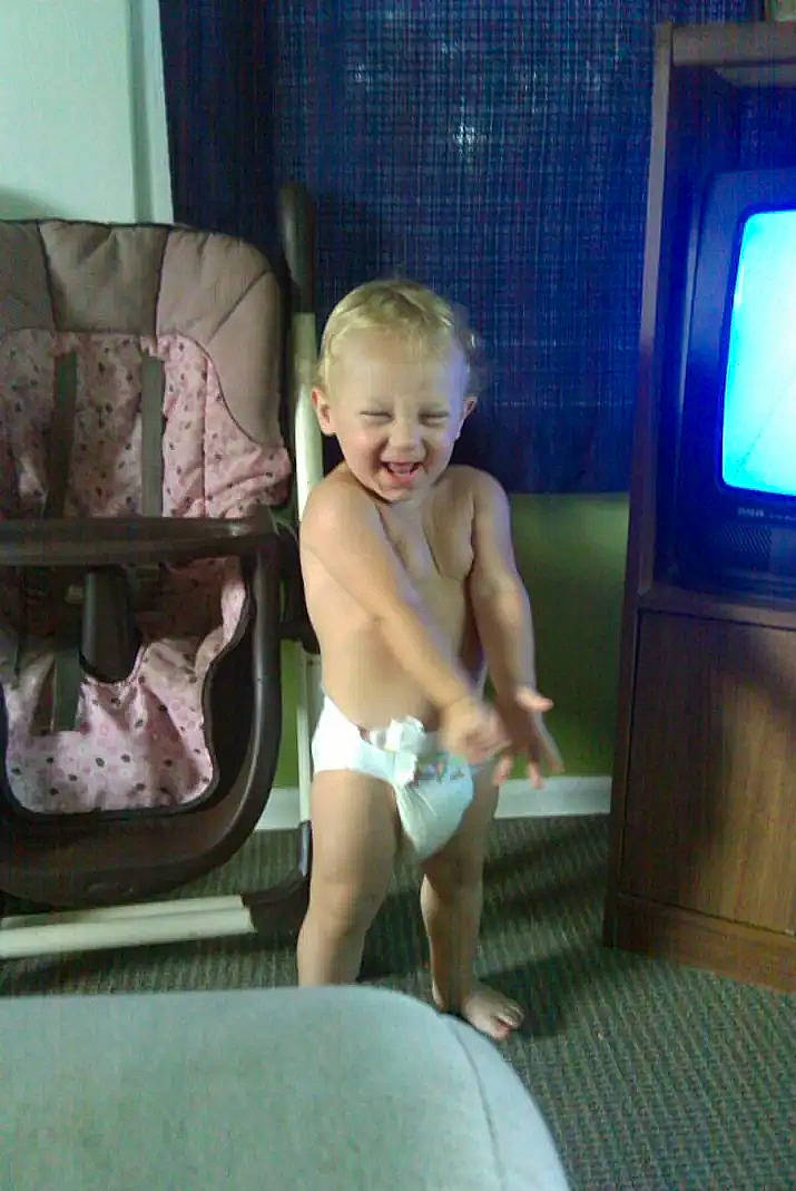 Collin is registered to the contest to win money with this photo: baby, barechested, chest, child, comfort, flooring, fun, human_leg, knee, leisure, living_room, person, room, shorts, sitting, smile, television, thigh, thumb, toddler