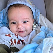 Tobias joined the competition — help win amazing prizes! baby, blanket, blue, child, closeup, clothing, cozy, cute, face, happy, hat, indoors, infant, newborn, person, portrait, smiling, soft, warm, white