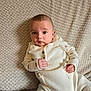 Tobias is registered to the contest to win money with this photo: baby, infant, knitwear, blanket, beige, texture, clothing, person, portrait, cute, indoor, child, small_hands, sitting, cozy, soft, warm, looking, curious, expression