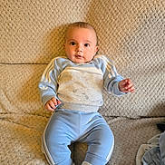 Tobias joined the competition — help win amazing prizes! baby, child, infant, blue_clothing, tracksuit, socks, couch, beige, texture, indoor, portrait, cute, young, sitting, person, face, smiling, cozy, soft, comfortable
