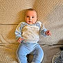 baby, child, infant, blue_clothing, tracksuit, socks, couch, beige, texture, indoor, portrait, cute, young, sitting, person, face, smiling, cozy, soft, comfortable