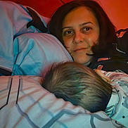 Iris Calissa Maria joined the competition — help win amazing prizes! woman, baby, bed, pillow, blanket, sleepwear, indoor, resting, face, hair, comfort, family, parent, child, night, warm_light, cozy, intimate, closeup, portrait