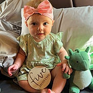 Wrenlee joined the competition — help win amazing prizes! baby, child, infant, pink_bow, headband, green_dress, stuffed_toy, dinosaur_toy, bed, pillow, wooden_sign, five_months, sitting, indoors, cute, portrait, smiling, childhood, soft_toy, person