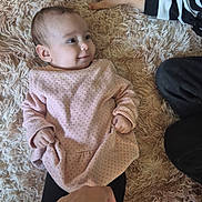 Ayla a rejoint le concours — aidez-le/la à gagner de superbes lots ! baby, child, hand, pink_clothing, rug, fluffy_rug, smile, person, infant, indoor, soft_texture, black_pants, striped_sleeve, footwear, playful, family, casual, human, cute, relaxing