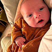 Nans a rejoint le concours — aidez-le/la à gagner de superbes lots ! baby, infant, child, face, hand, clothing, brown_outfit, close_up, skin, person, newborn, resting, expression, indoor, soft_lighting, holding, comfort, cute, portrait, human