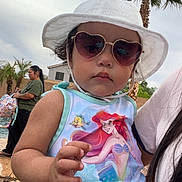 Gabby joined the competition — help win amazing prizes! toddler, child, sunglasses, heart_shaped, hat, white_hat, tank_top, ariel, the_little_mermaid, outdoor, palm_tree, woman, pool, summer, sunny, person, portrait, hand, casual, daytime