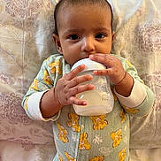 Madiha joined the competition — help win amazing prizes! baby, bed, bottle, cartoon_lion, child, curious, cute, face, feeding, hands, indoors, infant, lying_down, nursery, onesie, person, pillow, portrait, sleepwear, small_hands