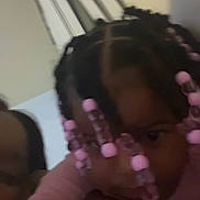 Malani is registered to the contest to win money with this photo: child, hair, beads, braids, face, person, indoor, blur, closeup, hairstyle, pink, head, people, portrait, background, dark, skin, human, young