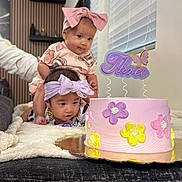 Luna And Adriana is registered to the contest to win money with this photo: baby, birthday_cake, blanket, bow, celebration, child, curious, cute, decor, family, flower, headband, indoor, person, pink, purple, smiling, table, toddler, yellow