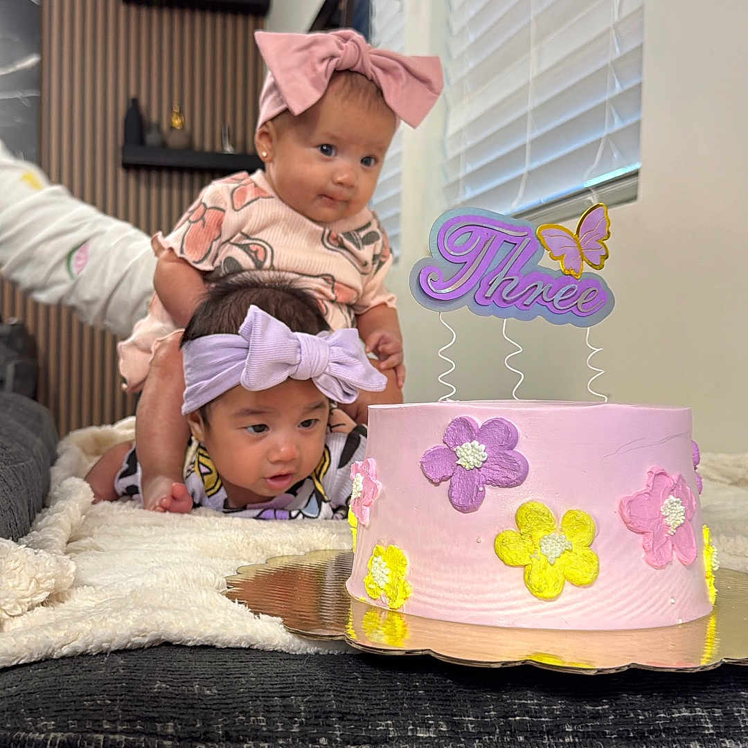 Luna And Adriana is registered to the contest to win money with this photo: baby, birthday_cake, blanket, bow, celebration, child, curious, cute, decor, family, flower, headband, indoor, person, pink, purple, smiling, table, toddler, yellow