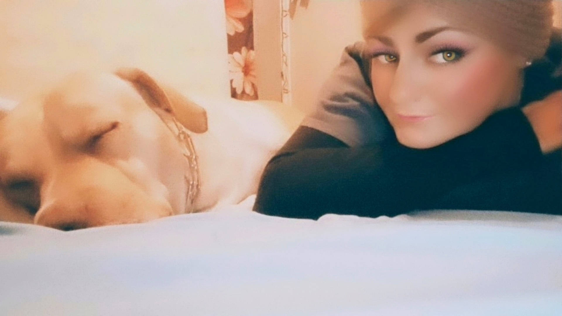 bed, calm, casual_clothing, chain_collar, closeup, companion, cozy, dog, face, floral_background, human, indoor, person, pet, portrait, relaxation, resting, sleeping, soft_lighting, warmth