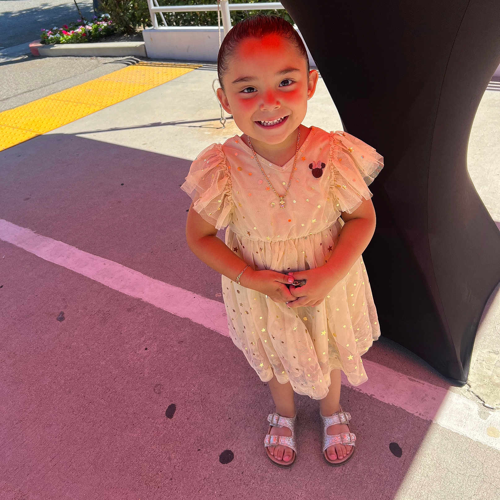Destinie is registered to the contest to win money with this photo: background, bracelet, car, child, concrete, dress, flowerbed, girl, happy, necklace, outdoor, pavement, person, railing, sandals, shadow, smile, sparkly, standing, sunlight