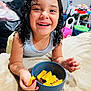 child, smiling, curly_hair, wet_hair, blue_bowl, mango, food, chili_powder, blanket, indoor, toys, colorful, happy, face, hand, arm, person, playing, bedroom, casual