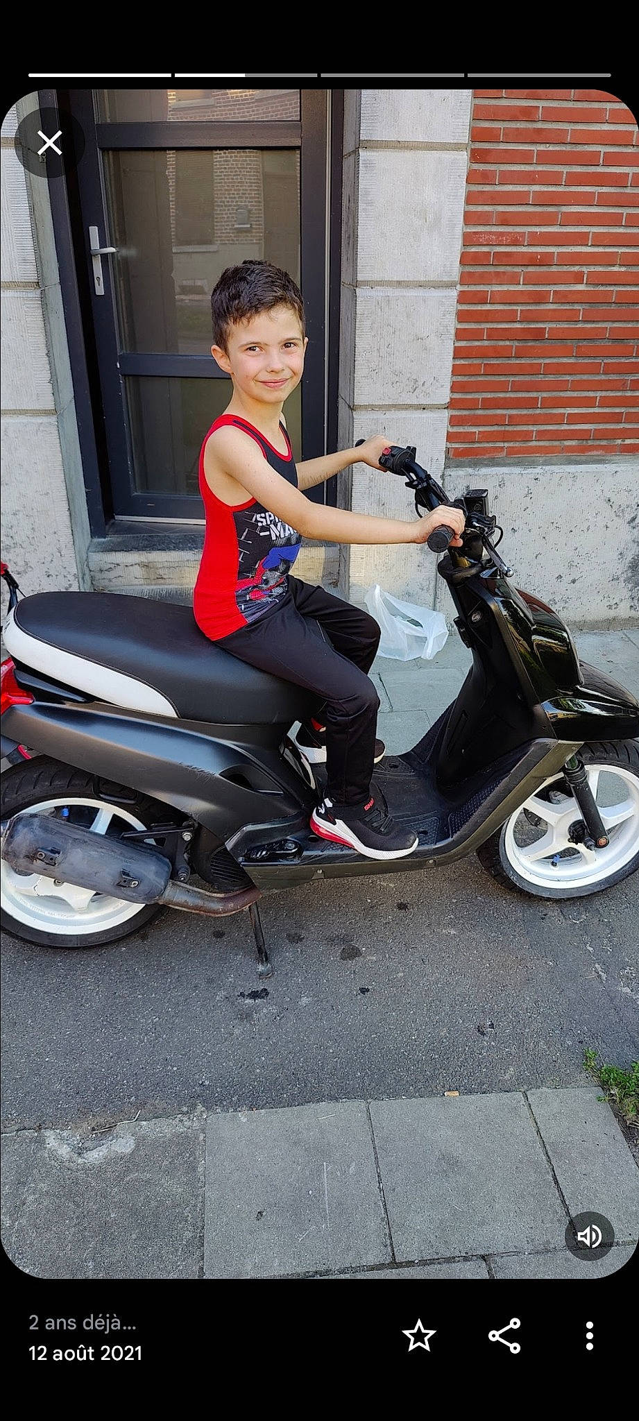 Tayron a rejoint le concours — aidez-le/la à gagner de superbes lots ! arm, auto_part, automotive_design, automotive_exterior, automotive_lighting, automotive_tire, automotive_wheel_system, fender, headlamp, human_leg, joy, moped, motor_vehicle, person, rim, scooter, sitting, smile, thigh, tire