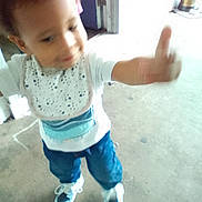Kentrell Simmons is registered to the contest to win money with this photo: toddler, child, blur, thumbs_up, smile, bib, indoor, doorway, concrete_floor, shoes, blue_pants, white_shirt, happy, motion, young_child, person, casual_clothing, small_child, cute, playful
