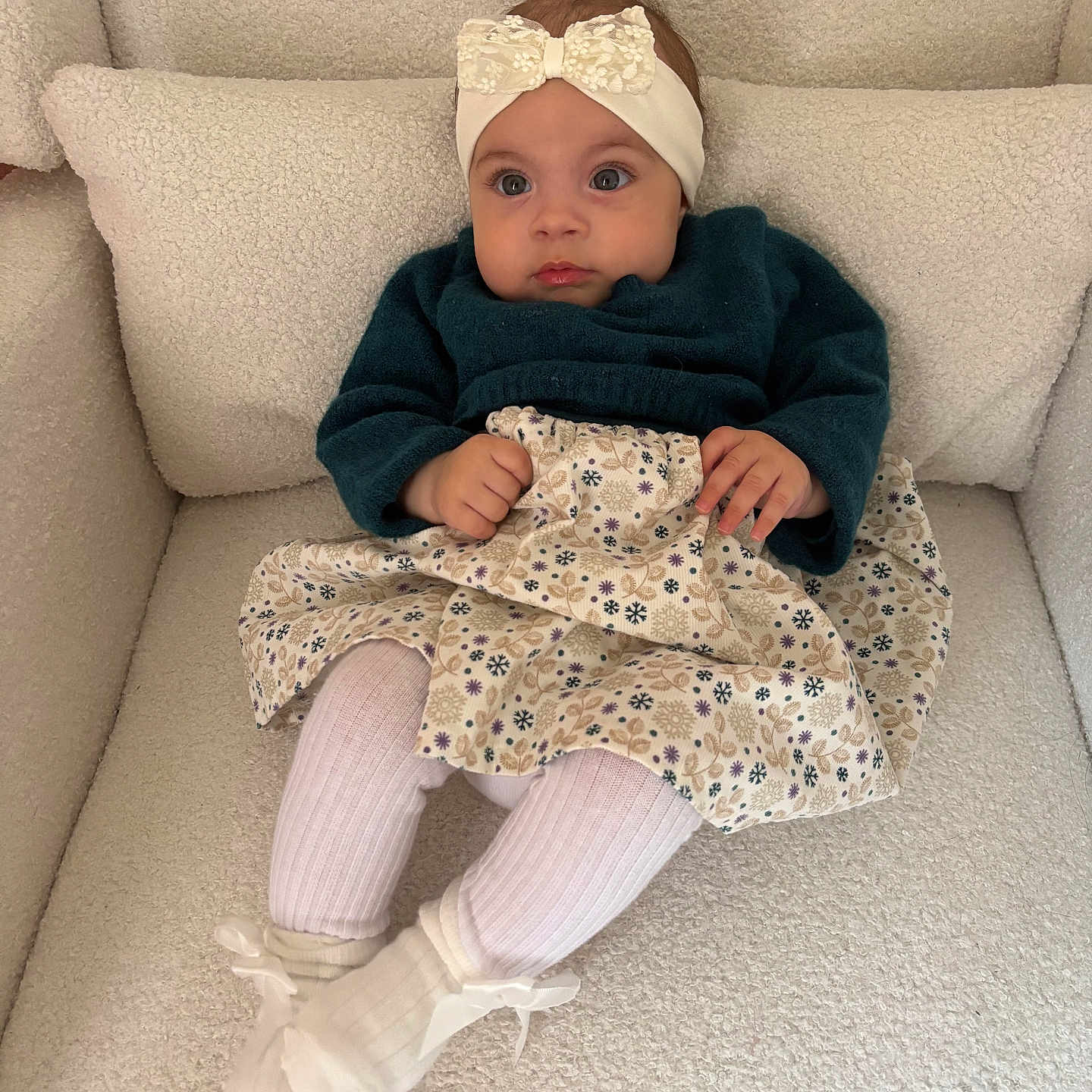 Veroccilia participe au concours pour gagner de l'argent avec cette photo : armchair, baby, bow, child, cozy, curious, cute, fashion, floral_pattern, headband, indoor, plush, portrait, seated, skirt, small_hands, socks, sweater, textile, white_socks