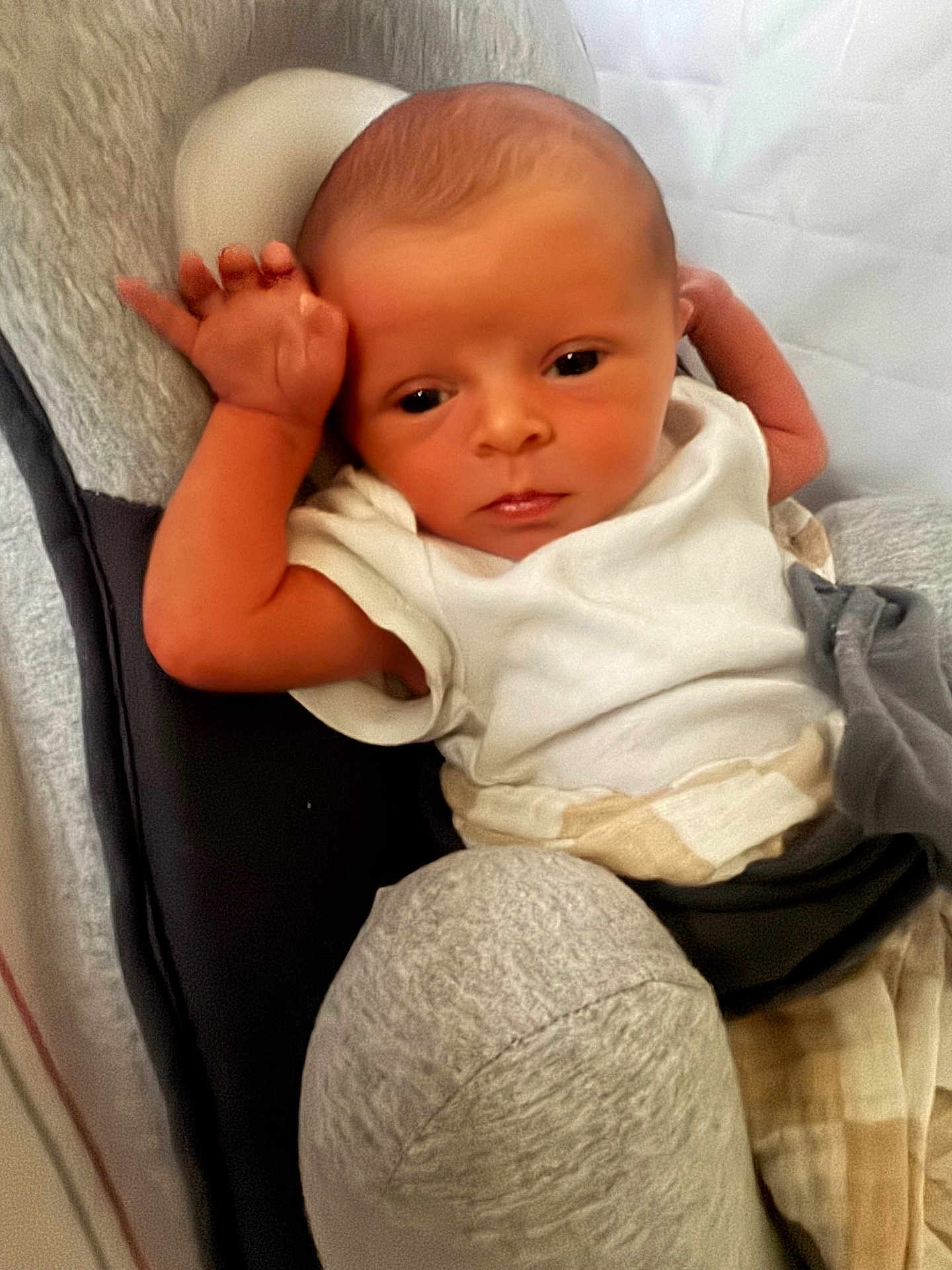Axel is registered to the contest to win money with this photo: baby, newborn, infant, child, white_onesie, blanket, cushion, seat, indoor, face, arm, hand, skin, expression, resting, portrait, clothing, comfort, young, person