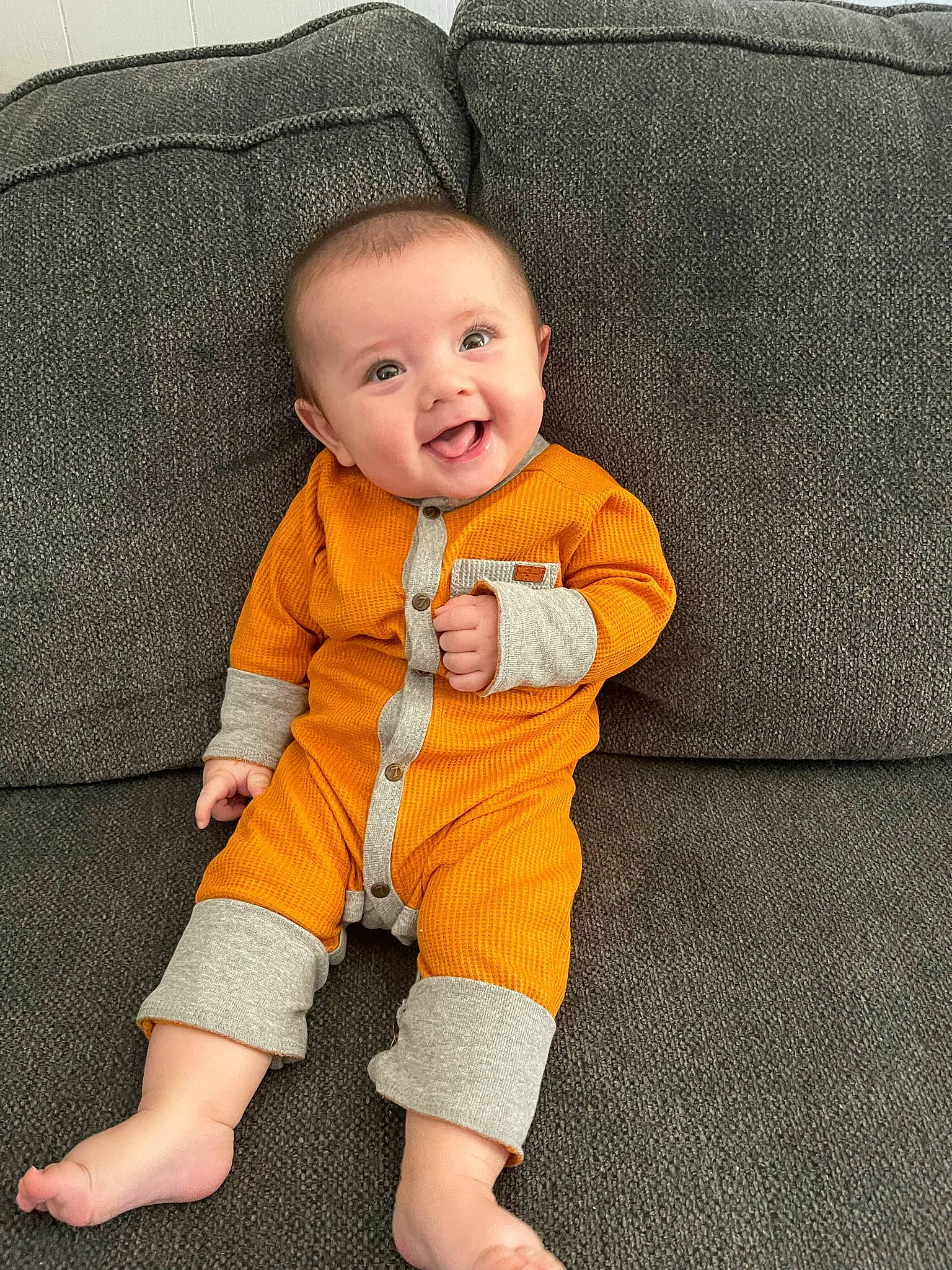 Levi is registered to the contest to win money with this photo: baby, baby_toddler_clothing, child, collar, comfort, couch, face, floor, flooring, head, outerwear, person, product, sitting, skin, sleeve, smile, t_shirt, textile, toddler