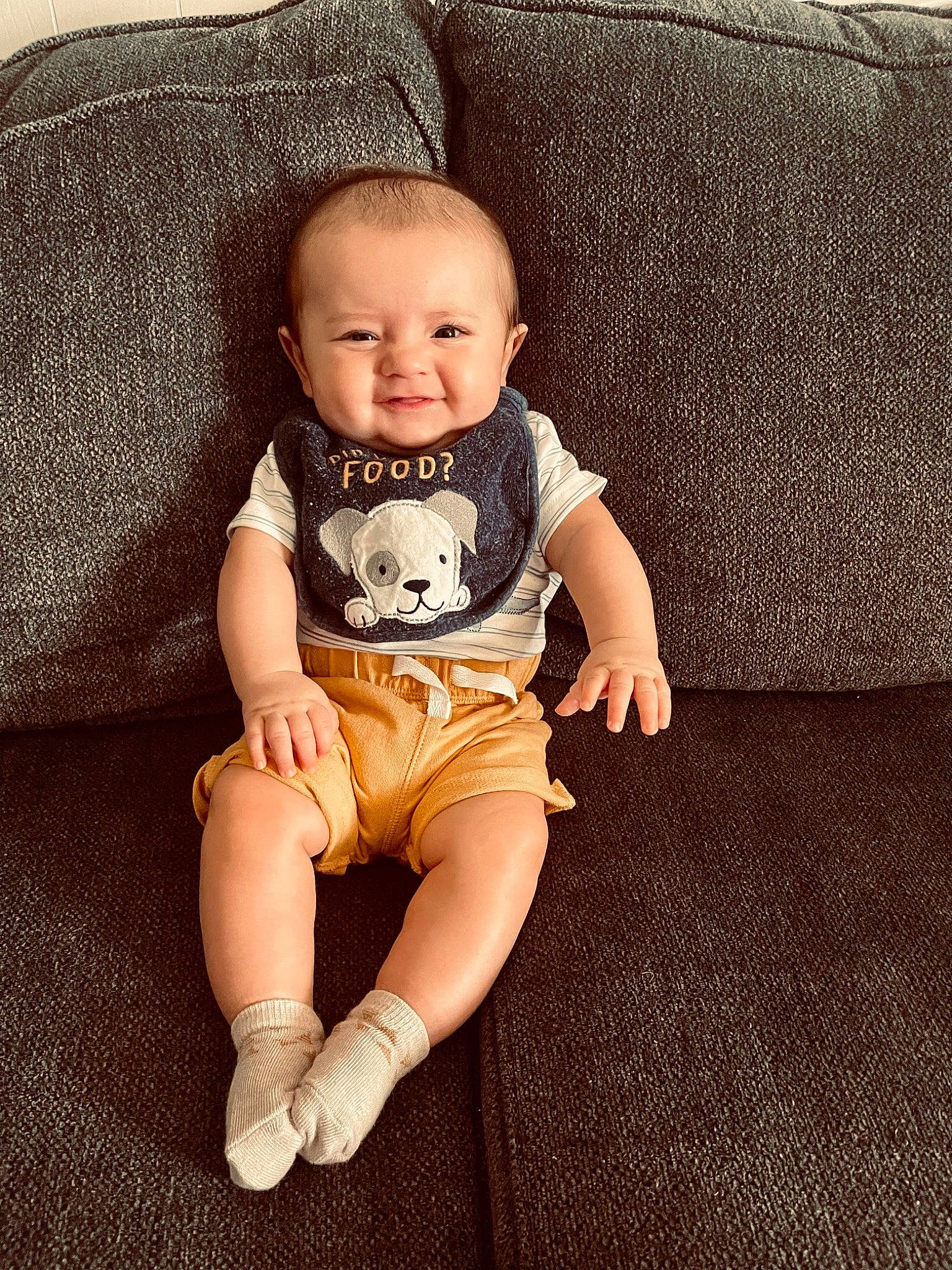 Levi is registered to the contest to win money with this photo: arm, baby, baby_toddler_clothing, comfort, couch, eye, finger, flash_photography, flooring, happy, head, iris, knee, leg, person, shorts, skin, sleeve, smile, t_shirt