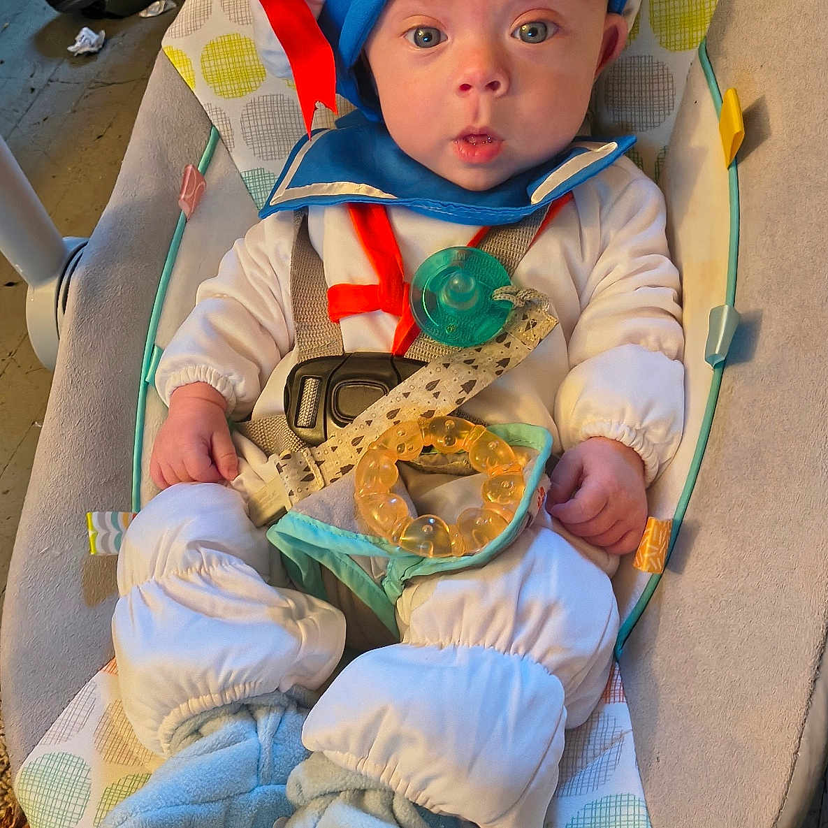 Robbie joined the competition — help win amazing prizes! baby, infant, child, sailor_costume, hat, blue_eyes, wide_eyed, pacifier, bouncer, seated, portrait, indoors, baby_clothing, white_outfit, blue_booties, baby_toy, toy_strap, patterned_blanket, carpet, funny_costume