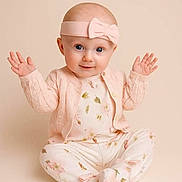 Leonie is registered to the contest to win money with this photo: baby, infant, child, pink_headband, bow, floral_pajamas, cardigan, sitting, raised_hands, cute, portrait, studio, soft_lighting, smiling, innocent, pastel_colors, face, eyes, hands, background