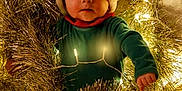 Marceau a rejoint le concours — aidez-le/la à gagner de superbes lots ! baby, celebration, child, christmas, cute, decoration, fairy_lights, festive, fun, glowing, green_clothing, holiday, indoors, portrait, red_and_white_stripes, santa_hat, seasonal, smiling, tinsel, wreath