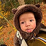 Marceau a rejoint le concours — aidez-le/la à gagner de superbes lots ! baby, child, face, tongue, hoodie, brown_clothing, baby_carrier, forest, autumn, leaves, trees, outdoor, nature, playful, cute, person, infant, fall_season, wooded_area, expression