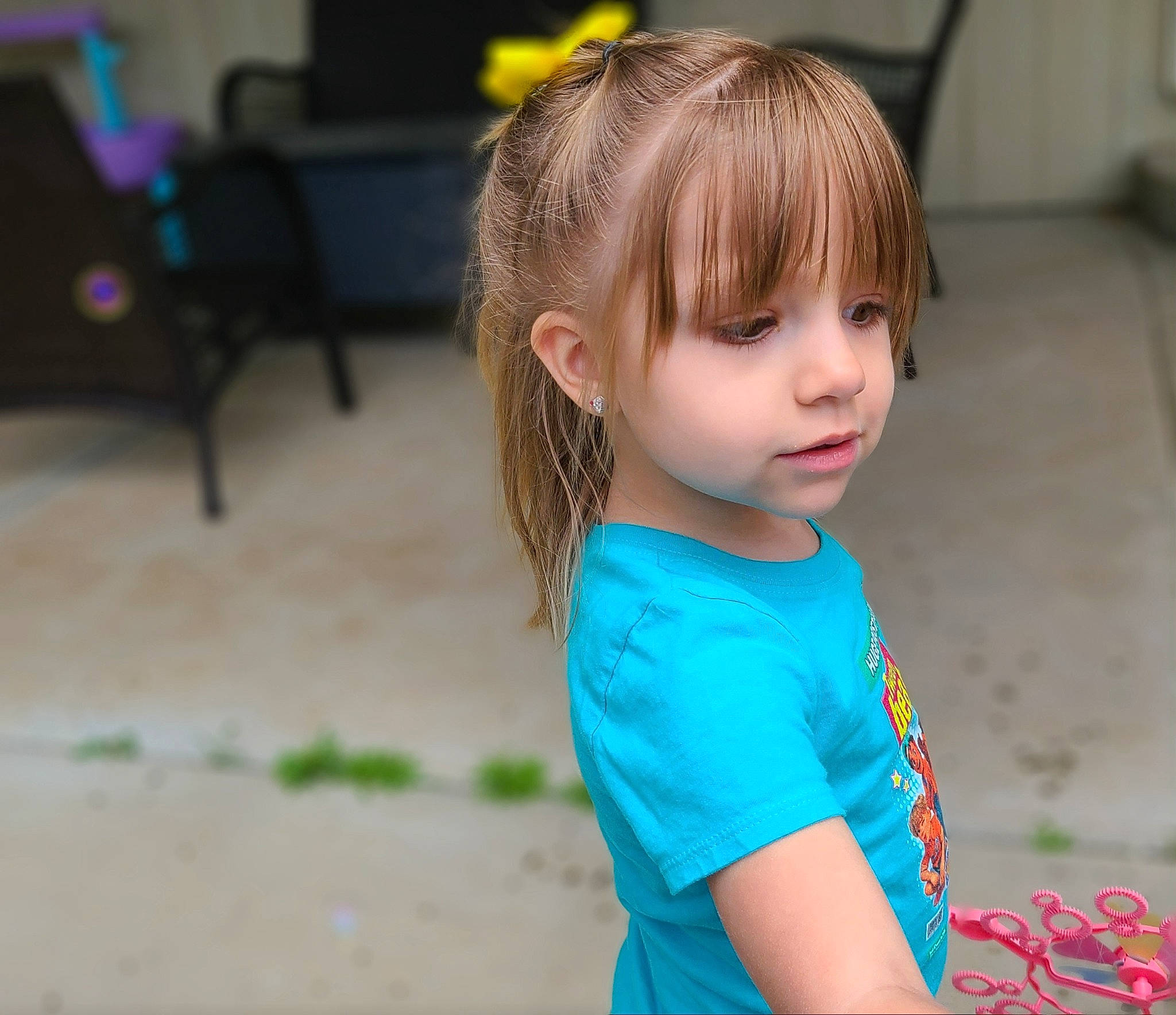 Charlee is registered to the contest to win money with this photo: bangs, blond, brown_hair, cheek, child, electric_blue, eye, flooring, fun, grass, happy, iris, leisure, neck, person, recreation, sitting, skin, sleeve, t_shirt