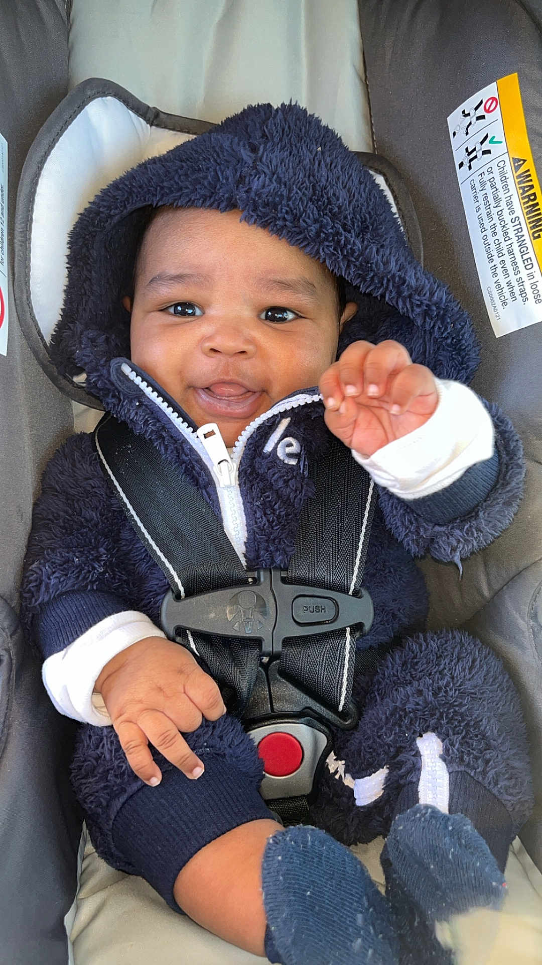Kycen is registered to the contest to win money with this photo: baby, child, car_seat, fuzzy_clothing, hood, smiling, hand, footwear, socks, safety_harness, cute, infant, indoors, person, closeup, happy, young, seat, zipped_jacket, playful