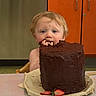 child, toddler, cake, chocolate_cake, chocolate, strawberries, food, messy, face, blue_eyes, hair, kitchen, orange_cabinet, table, plate, fingers, eating, happy, indoor, person