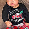 Noah is registered to the contest to win money with this photo: baby, child, infant, christmas, holiday_clothing, plaid_pants, black_shirt, red_pants, sitting, indoors, couch, cozy, cute, festive, face, expression, young_child, portrait, person, seasonal