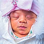 baby, sleeping, infant, pink_bow, headband, white_clothing, fur_hood, close_up, face, cute, newborn, soft_texture, portrait, child, adorable, peaceful, button, embroidery, warm, cozy