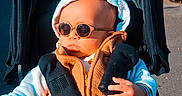 Kameron participe au concours pour gagner de l'argent avec cette photo : baby, child, cool, fashionable, hand, hood, infant, jacket, orange_clothing, outdoor, pavement, playground, portrait, seatbelt, shade, stroller, stroller_canopy, sunglasses, sunny, urban