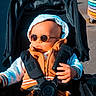 baby, child, cool, fashionable, hand, hood, infant, jacket, orange_clothing, outdoor, pavement, playground, portrait, seatbelt, shade, stroller, stroller_canopy, sunglasses, sunny, urban