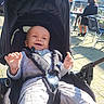 Kameron participe au concours pour gagner de l'argent avec cette photo : adult, baby, cafe, chairs, clothing, cobblestone, hand, happy, harness, hood, infant, outdoor, pavement, people, portrait, seat, smile, stroller, sunlight, table