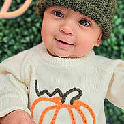 Riley joined the competition — help win amazing prizes! autumn, baby, child, closeup, cozy, cute, face, green_background, hand, happy, headwear, indoors, knit_hat, person, portrait, pumpkin_design, smiling, sweater, warm_clothing, young_child