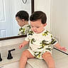 Victor joined the competition — help win amazing prizes! toddler, child, mirror, bathroom, sink, countertop, faucet, reflection, white_wall, dinosaur_print, shorts, shirt, barefoot, curious, indoor, modern, plumbing, black_faucet, person, casual_clothing