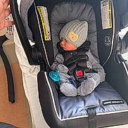 Lukas is registered to the contest to win money with this photo: baby, newborn, car_seat, sleeping, hat, pacifier, striped_pajamas, infant, child, hand, seatbelt, fabric, indoor, person, protection, soft_lighting, cushion, black, gray, cozy