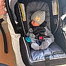 baby, newborn, car_seat, sleeping, hat, pacifier, striped_pajamas, infant, child, hand, seatbelt, fabric, indoor, person, protection, soft_lighting, cushion, black, gray, cozy