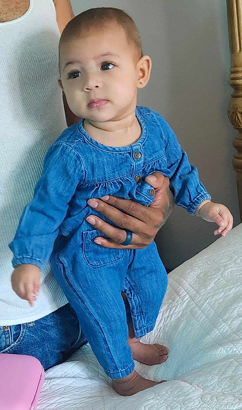 Love is registered to the contest to win money with this photo: adult_hand, baby, bed, bedspread, casual_clothing, child, curious, cute, denim_outfit, earring, foot, hand, holding, indoor, infant, jeans, person, portrait, skin, white_tank_top