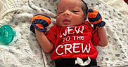 Noah joined the competition — help win amazing prizes! newborn, baby, infant, child, portrait, lying_down, blanket, red_shirt, black_pants, mittens, pacifier, bed, bedding, indoors, face, eyes_open, clothing, text_on_shirt, cozy, family_photo
