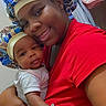 baby, child, siblings, portrait, selfie, smiling, cuddling, bonnet, matching_outfits, red_shirt, infant, newborn, family, indoor, nursery, bedroom, blanket, gloves, purple_hearts, text_overlay