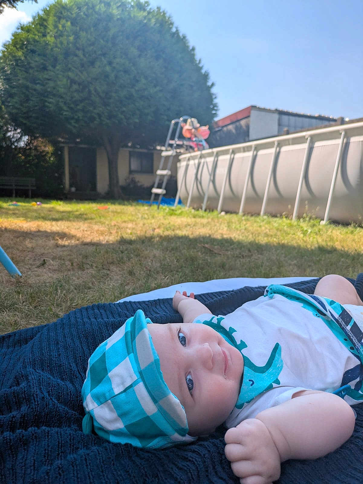 éveun a rejoint le concours — aidez-le/la à gagner de superbes lots ! baby, child, smiling, hat, blanket, grass, backyard, outdoor, sunny, pool, tree, blue, white, clothing, person, nature, daylight, recreation, relaxation, infant