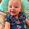 baby, smiling, infant, child, floral_clothing, blanket, cushion, happy, cute, face, portrait, indoors, comfort, soft, head, skin, person, apparel, seated, expression