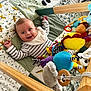 baby, infant, play_mat, plush_toy, wooden_play_gym, smiling, striped_clothing, happy, child, indoor, face, colorful, toy, baby_toys, cushion, floor, person, cute, playtime, toddler