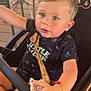 toddler, child, stroller, pacifier, bracelet, clothing, outdoor, chair, wooden_floor, safety_bar, baby, person, cute, casual, seat, curious, young_child, short_hair, daylight, relaxed