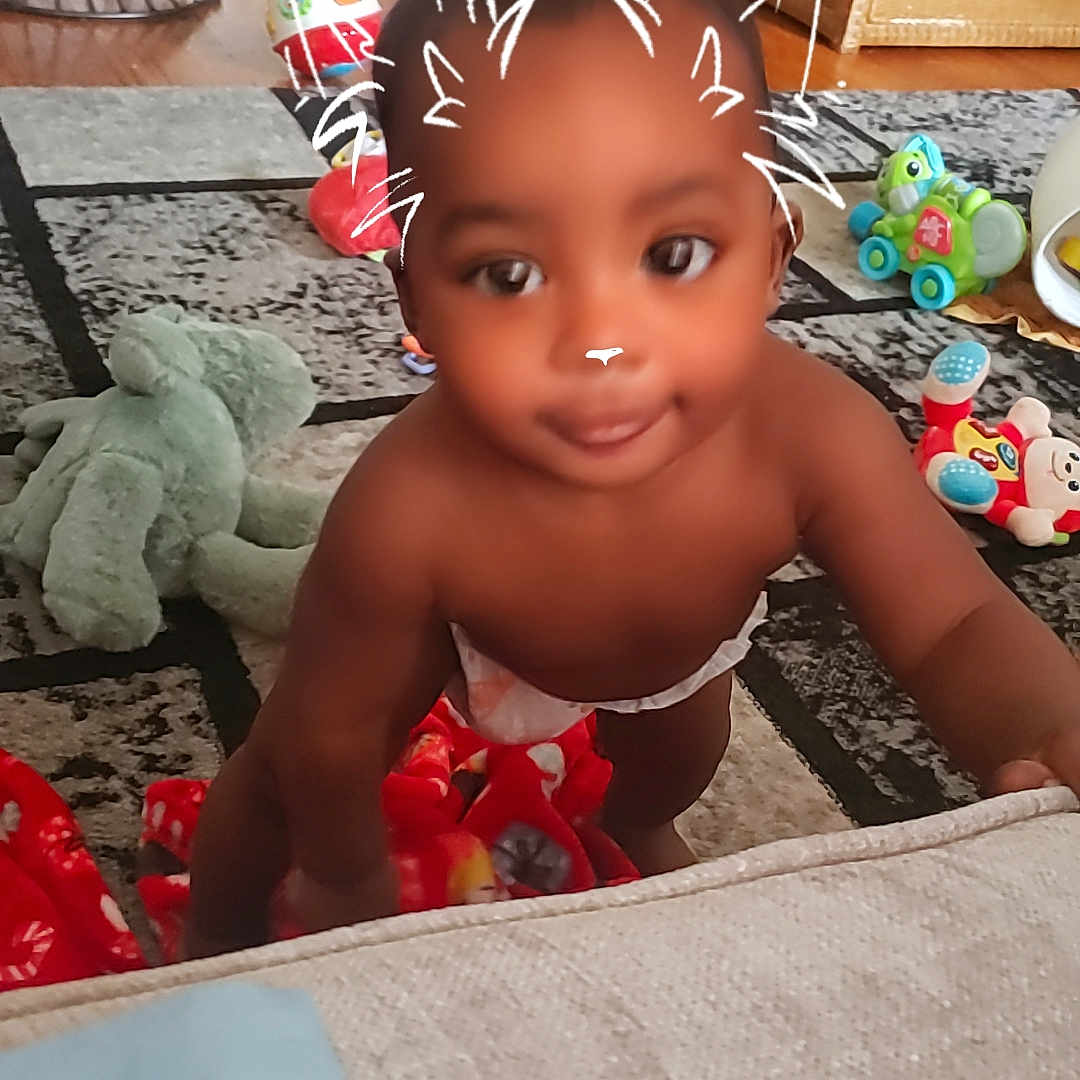 Zamiq is registered to the contest to win money with this photo: baby, basket, blanket, carpet, cat_ears, child, crawling, cute, diaper, filter, furniture, indoor, living_room, person, playful, smiling, soft_toy, toddler, toy, wood_floor