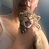 person, kitten, cat, animal, pet, holding, close_up, indoor, tank_top, mouth_open, cute, feline, face, hand, small_animal, young, fur, whiskers, expression, light