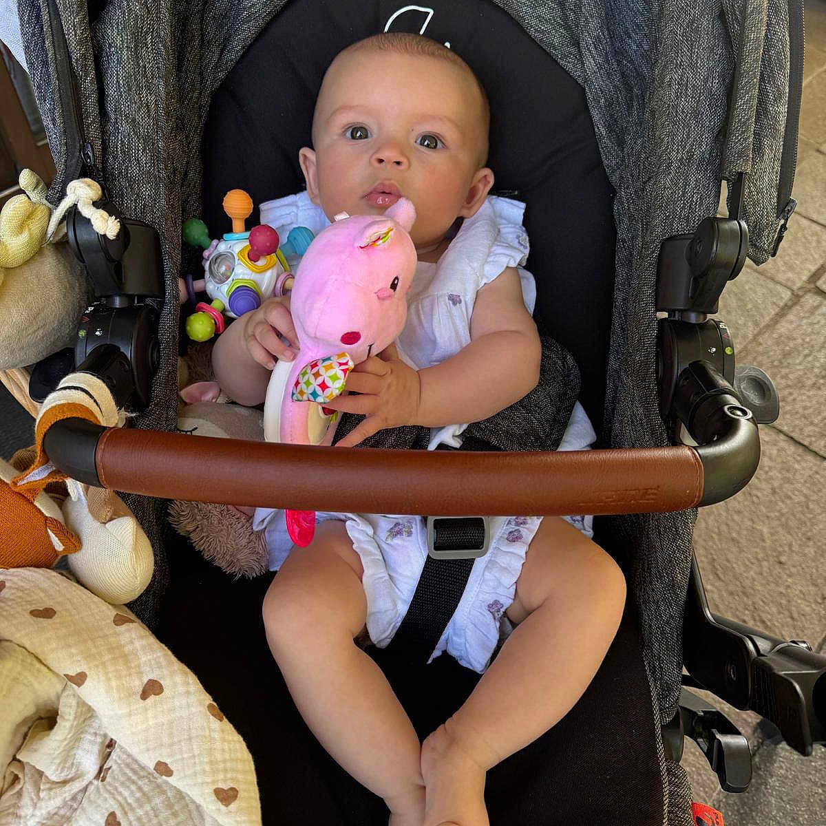 Mia a rejoint le concours — aidez-le/la à gagner de superbes lots ! baby, blanket, child, clothing, comfort, curious, face, feet, hands, head, indoors, infant, legs, person, pink, plush_toy, seatbelt, sitting, stroller, toy